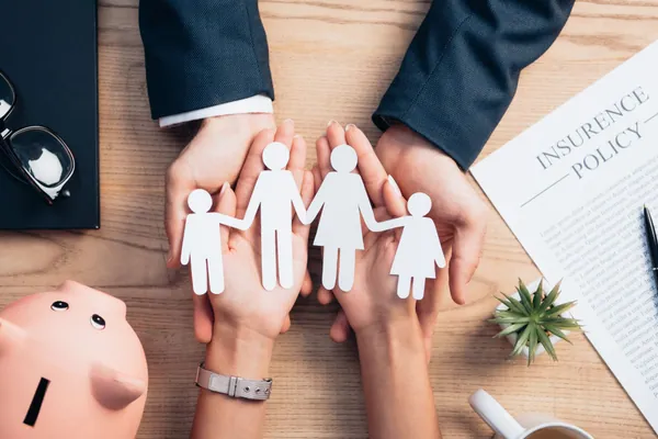 Cuánto cuesta un entierro en España en 2026: unas manos junto a una hucha resguardan a una familia de papel