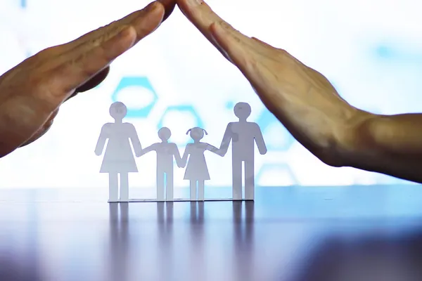 Cuánto cuesta un seguro de decesos en 2026: unas manos que protegen la silueta de papel de una familia