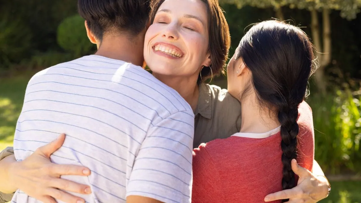 Una mujer abraza a su familia al aire libre, una imagen sobre el precio del seguro de decesos en Granada