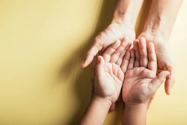 Qué hacer con las cenizas: unas manos adultas sostienen con cariño las manos de un niño