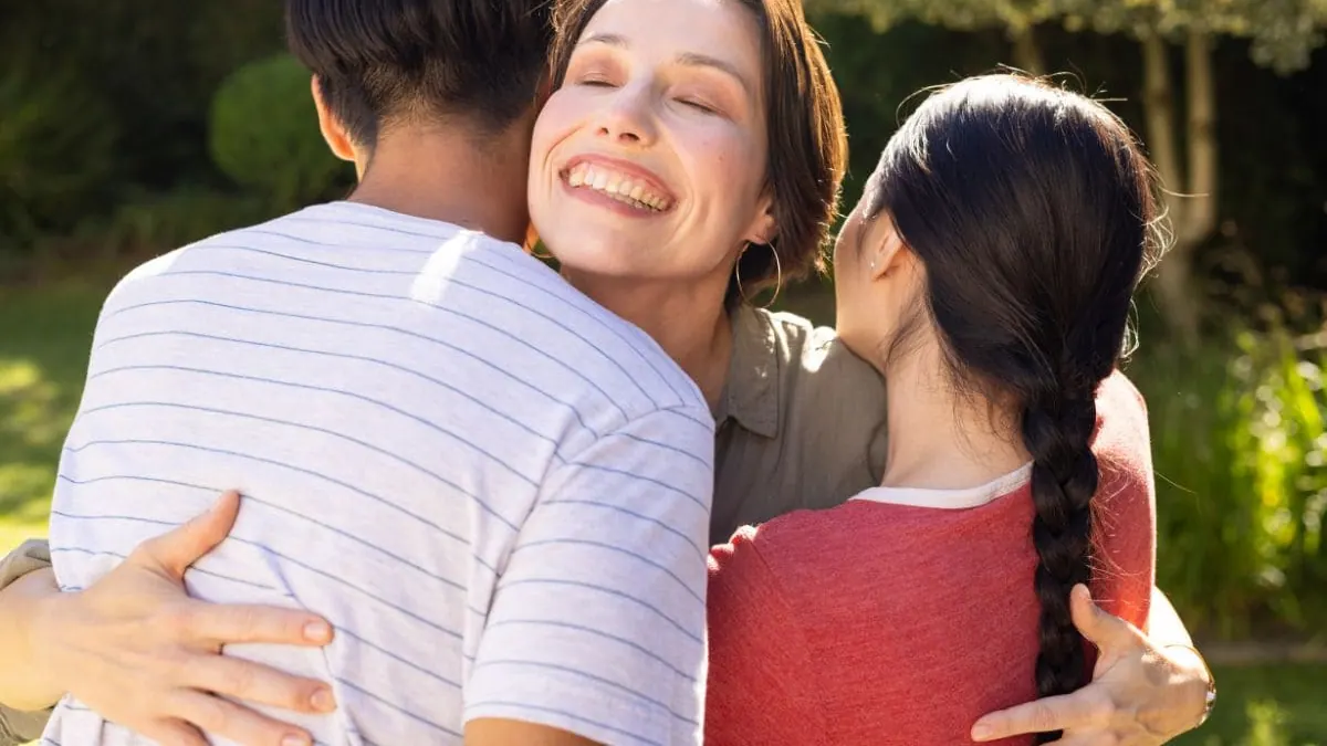 Una mujer abraza a su familia al aire libre, una imagen para la guía sobre seguro de decesos familiar