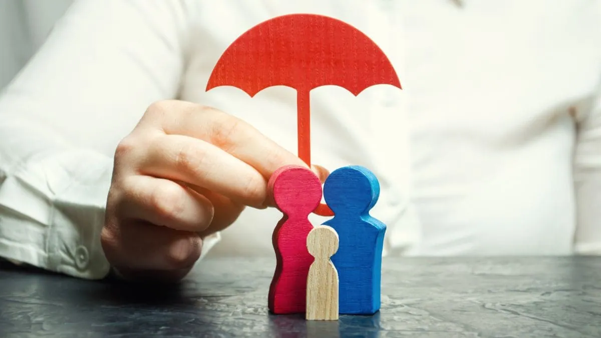 Un paraguas rojo protege a las figuras de una familia, una imagen del seguro de decesos en Las Palmas